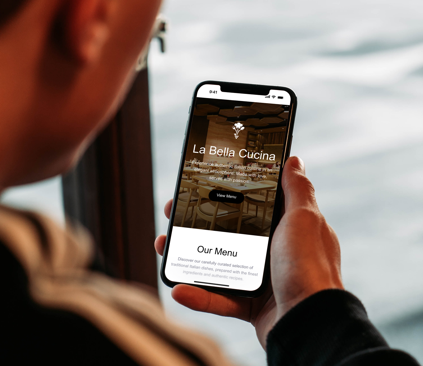 Person viewing an Italian restaurant digital menu on a smartphone with a warm interior background.