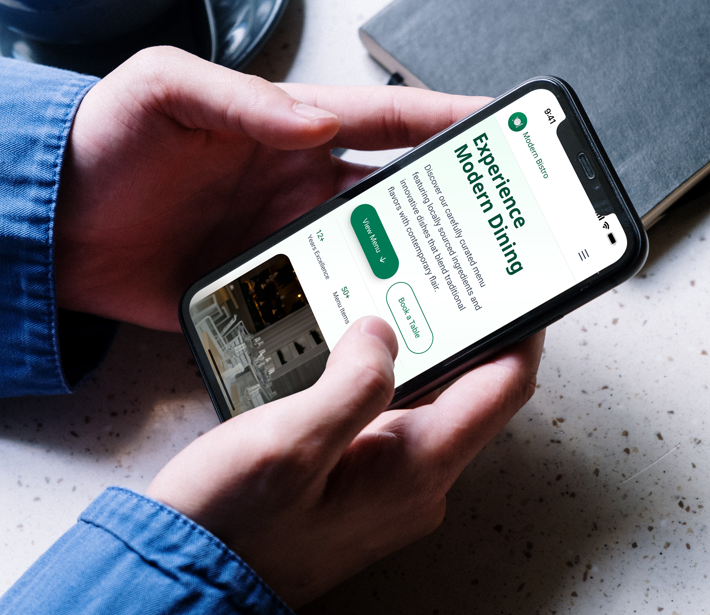 Person holding a smartphone showing a modern restaurant digital menu with reservation and view menu buttons.